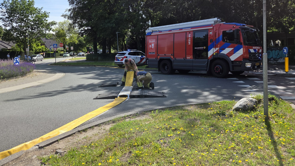De brandweer legt een slang aan om water uit de vijver van het Laapersveld te kunnen halen