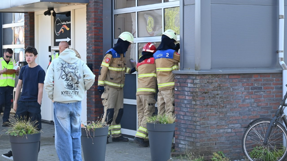 De jonge brandweerlieden bekijken het gebouw waar de brand woedt.
