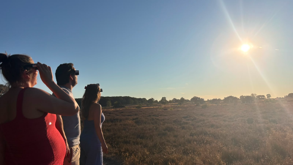 Geïnteresseerden kijken naar de eclips op de hei